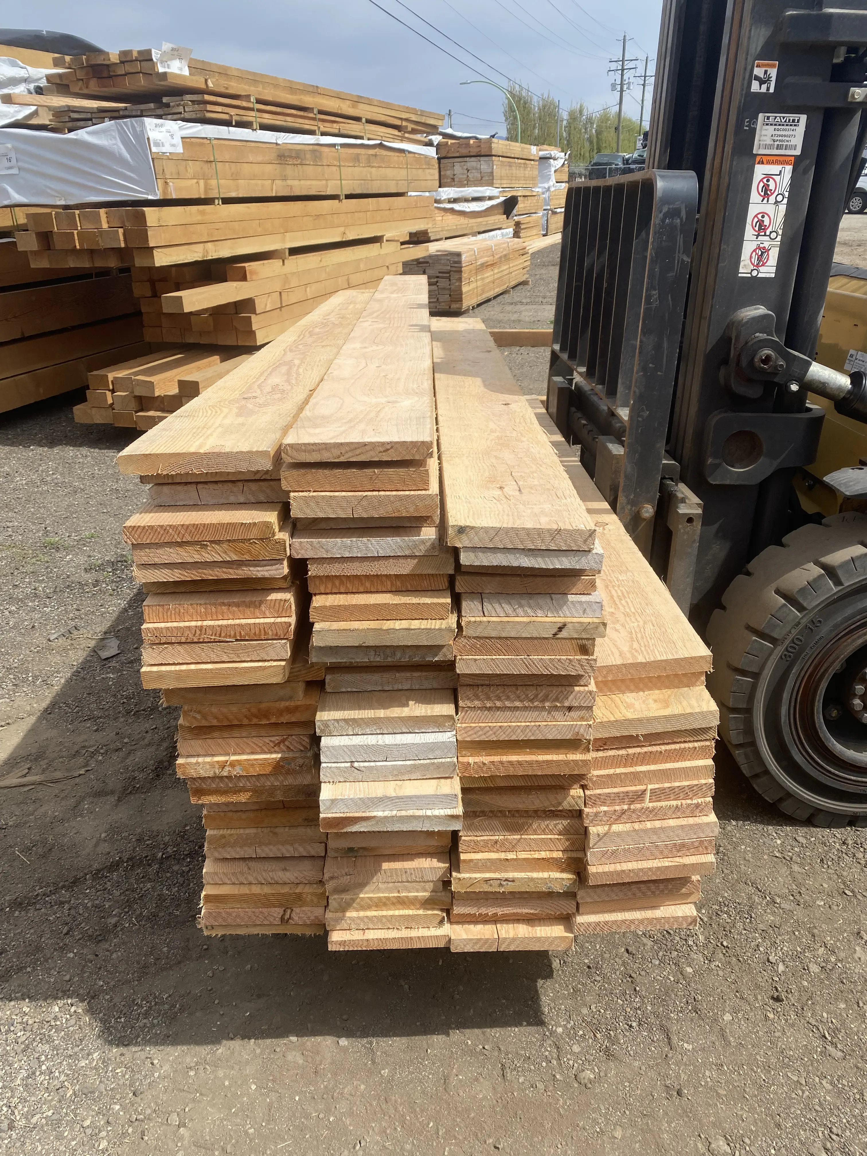 Large stack of fresh cedar boards on forklift forks ready for use